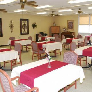 A dining room with neatly arranged tables and chairs, adorned with tablecloths and wall decorations.
