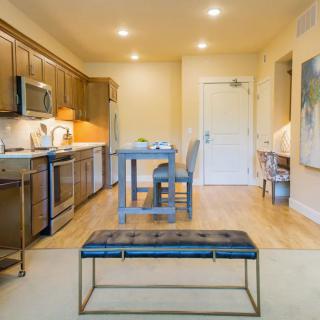 A modern kitchen and dining area with wooden cabinets, stainless steel appliances, and a small dining table.