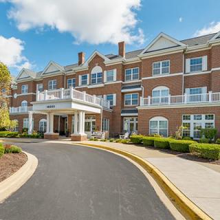 A large residential building with a brick exterior and a welcoming driveway entrance.