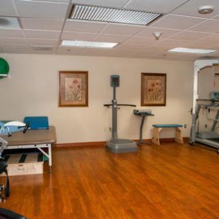 A gym room with various exercise equipment and wooden flooring.