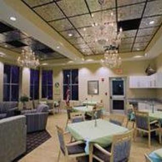 A modern dining and lounge area featuring chandeliers, tables, chairs, and large windows.