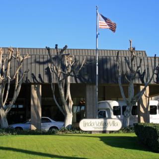 A building with an American flag, cars parked in front, and a sign on the lawn.