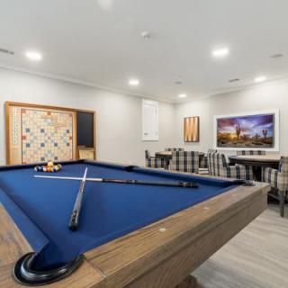 A modern game room featuring a blue pool table with cue sticks ready for play.