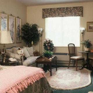 A cozy bedroom featuring elegant decor with a seating area and natural light coming through the window.