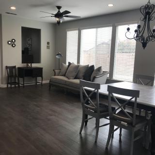 A modern living and dining area with hardwood floors, featuring a comfortable sofa, a large dining table, and a chandelier.