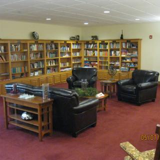 A cozy library corner with leather seating and well-stocked bookshelves.
