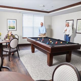 Seniors enjoying a game of pool in a leisure room.