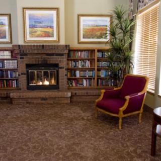 A cozy living room with a fireplace, bookshelves, and a red armchair.