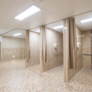 A modern, minimalist shower area featuring multiple stalls with curtains and tiled floors.