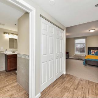 A view of a hallway with a closet, leading to a bathroom and bedroom.