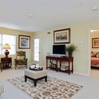 A well-decorated living room featuring comfortable seating, a television, and elegant artwork on the walls.