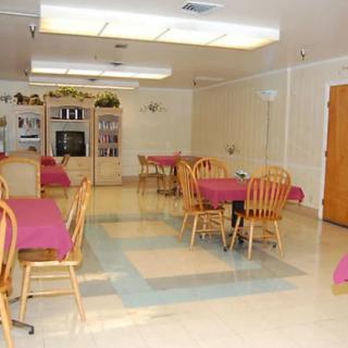 A neatly arranged dining room with tables and chairs covered in colorful linens.