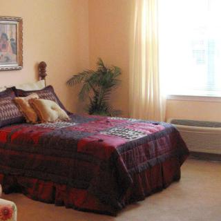 A cozy bedroom with a decorated bed and large window.