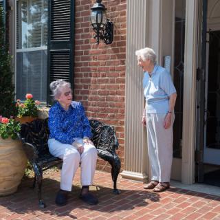 Two elderly women enjoying a conversation on a porch.