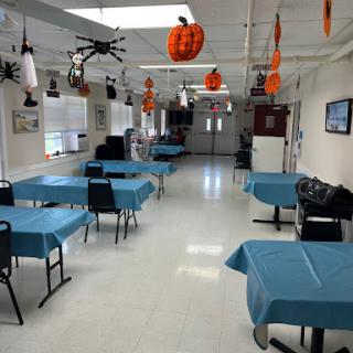 An empty dining area decorated for Halloween, featuring blue tables and festive decorations hanging from the ceiling.
