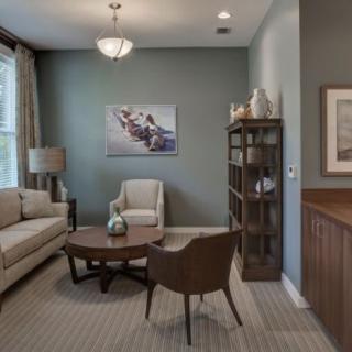 A cozy living room with a sofa, armchair, coffee table, and bookshelf.