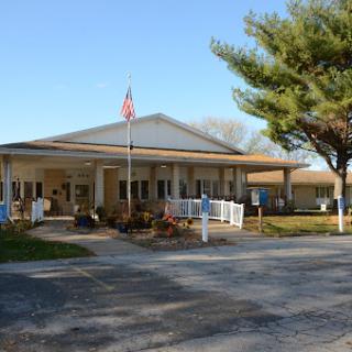 A community center featuring a welcoming entrance and an American flag, surrounded by trees and a parking area.