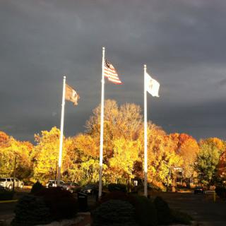 Flags standing tall against an autumn backdrop, with dark clouds looming overhead.