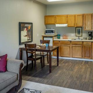 A cozy kitchen and living room area with wooden cabinets, a dining table, and a sofa.