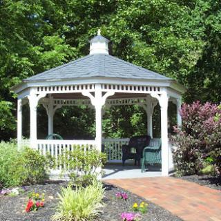 A charming white gazebo surrounded by lush greenery and colorful flowers.