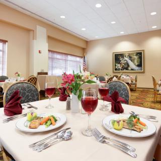 Elegant dining room with beautifully set tables, featuring dishes and wine glasses.
