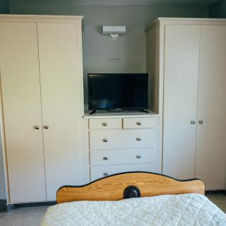 A cozy bedroom setup featuring a TV and ample storage.