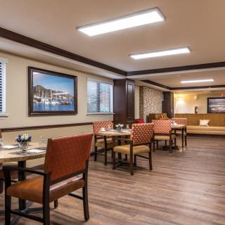 A modern dining area with tables, chairs, and framed artwork on the walls.