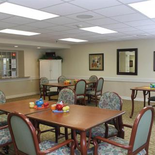A well-lit dining area with tables and chairs, decorated in a community space setting.