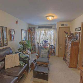 A cozy living room with a leather sofa, wooden furniture, and various decorative elements including plants and framed pictures.