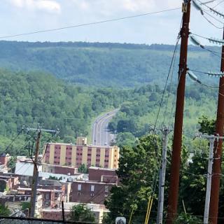 A view of a winding road leading through lush hills, with a town nestled below.