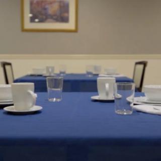 A neatly arranged dining setup with a blue tablecloth and cups on the table.