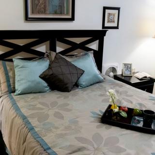 A cozy bedroom with a neatly made bed, accent pillows, and a decorative tray on the bed.