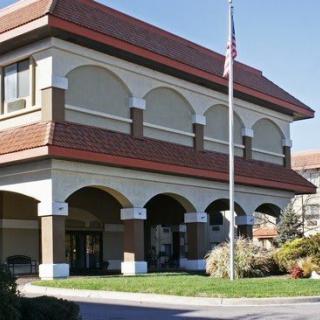A two-story building with a flagpole and landscaped surroundings.