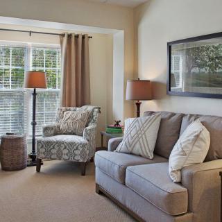 A cozy living room with a comfortable sofa and armchair by the window, plemented by warm lighting and tasteful decor.