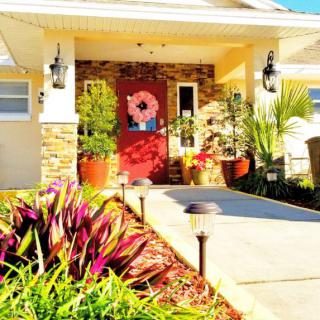 A cozy house entrance with decorative plants and a vibrant red door.