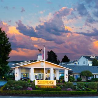 A charming building with a sign and flagpole stands against a backdrop of colorful sunset clouds.
