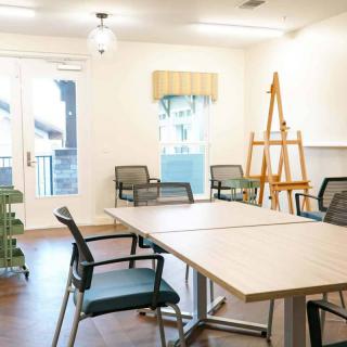 A bright and organized meeting room with tables, chairs, and an easel.