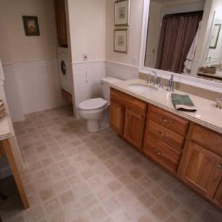 A clean and spacious bathroom featuring a large mirror, wooden cabinets, and tiled flooring.