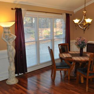 A cozy dining room with wooden flooring, a round table, chairs, and elegant lighting.