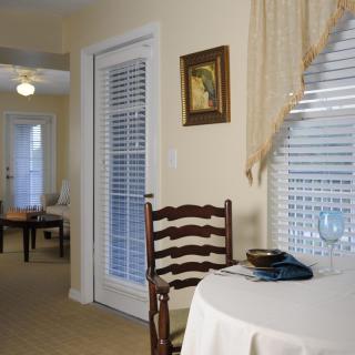 A cozy living room with a table and chair near a window with blinds.