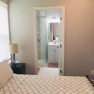 A cozy bedroom with an adjoining bathroom, featuring modern decor and soft lighting.