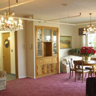 A cozy dining area featuring chandeliers, a wooden cabinet, and a set of table and chairs on a carpeted floor.