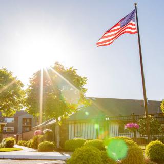 A bright sunny day with an American flag waving in front of a building.