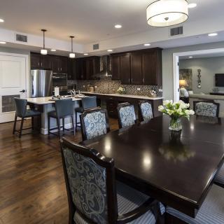 A modern open-plan kitchen and dining room with dark wood furniture and elegant lighting.
