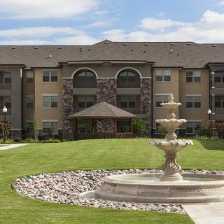 A three-story residential building with a central fountain and well-maintained lawn.