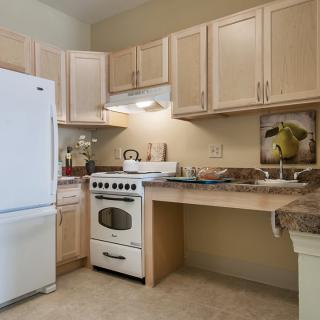 A modern kitchen featuring a refrigerator, stove, and wooden cabinets.
