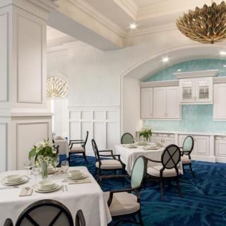 An elegant dining room with a luxurious blue carpet, stylish chandeliers, and beautifully set tables.