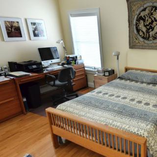 A tidy bedroom with a computer desk and wall decor.