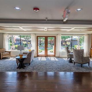 A spacious and well-lit lobby with comfortable seating and large windows overlooking a garden.