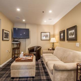 A cozy living room with a comfortable sofa, a wall-mounted television, and framed artwork.